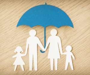 Paper,Family,Silhouette,With,Umbrella,On,Wooden,Background,-,Concept
